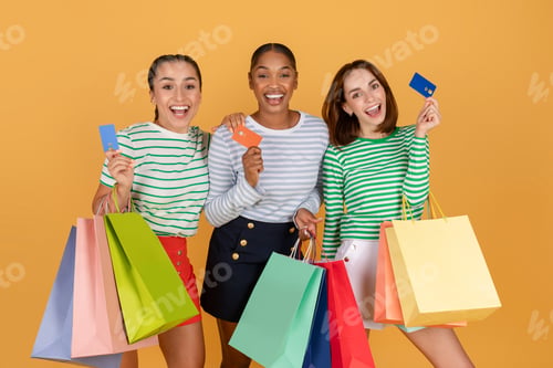 Preview: Three attractive young multiethnic ladies shopping together, using credit cards