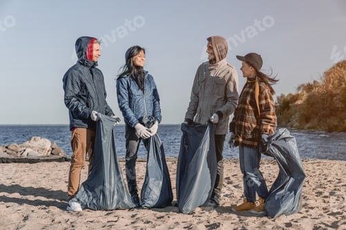 Preview: Front view shot of volunteers talking and smiling after cleaning the beach