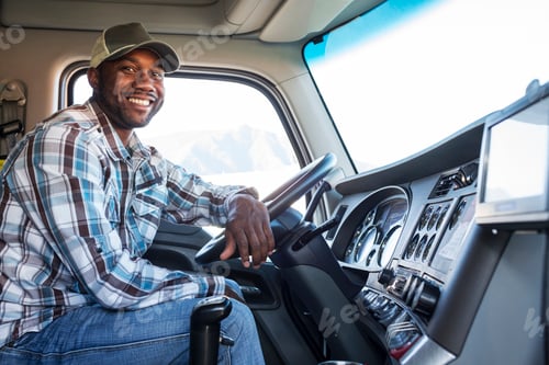 Preview: Black man truck driver in the cab of his commercial truck.