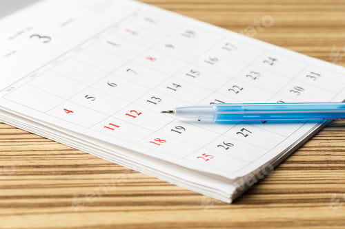 Preview: Planning for the month with a calendar and pen on a wooden table