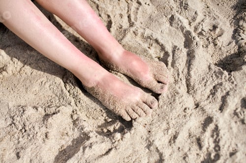 Preview: Bare feet on sunlit sandy beach