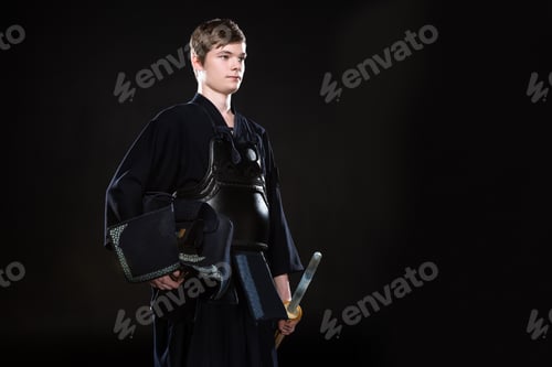 Preview: Young man holding kendo helmet and bamboo sword on black