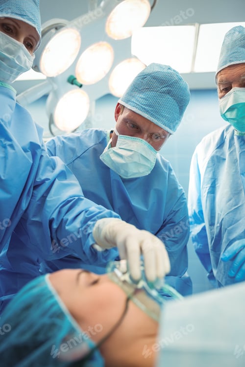 Preview: Team of surgeons adjusting oxygen mask on patient mouth in operation theater