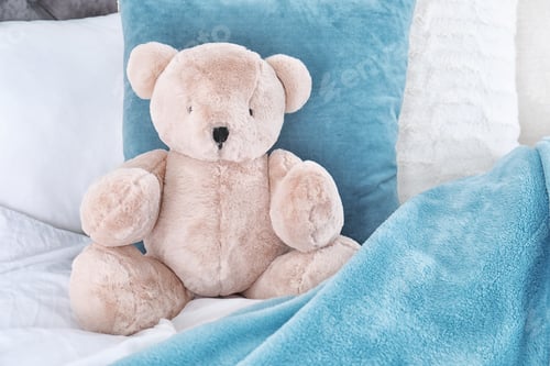 Preview: Cute teddy bear sitting on bed indoors. Space for text