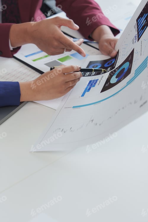 Preview: Business people analyzing financial charts and graphs at office desk