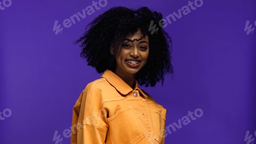 Preview: positive african american woman with braces smiling isolated on purple