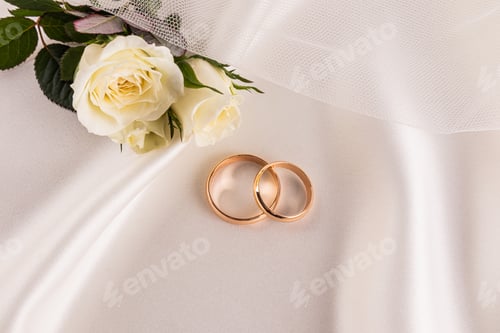 Preview: Two gold wedding rings lying on soft beige satin fabric. Concept Gold wedding rings