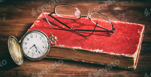 Preview: Pocket watch and eye glasses on an old book