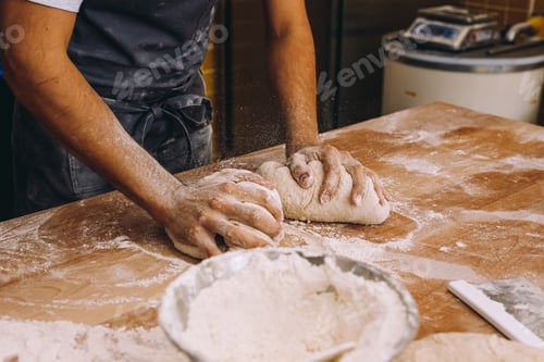 Preview: Anonymous man cook shaping dough in bakery