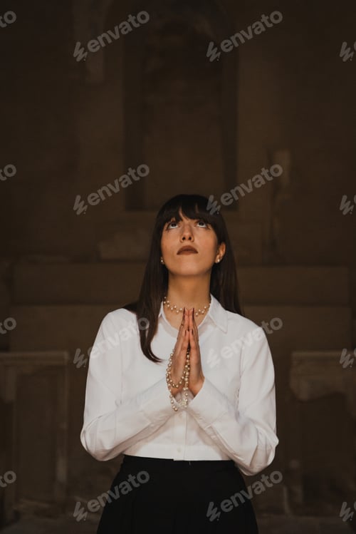 Preview: Devoted Young Woman Standing In The Church Praying With Hands Together