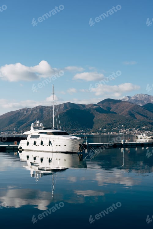 Preview: White single-deck yacht at the pier with mountains in the background
