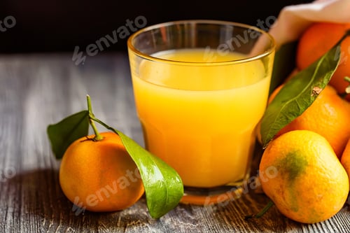 Preview: Glass of fresh juice and mandarins on table