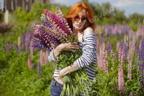 Preview: Young beautiful woman with redhead with bunch of flowers lupine