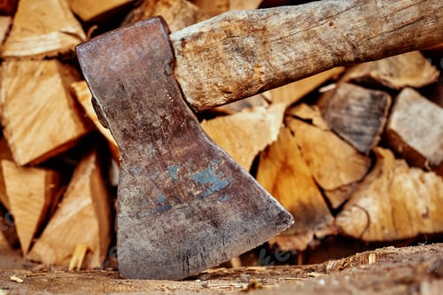 Preview: Close up of axe agains firewood background