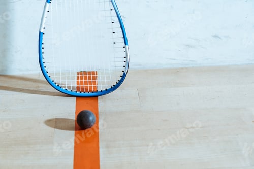 Preview: Squash racket and ball on wooden floor in four-walled court