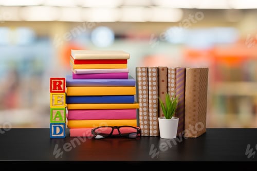 Preview: Stack of books on wooden table against blurred background