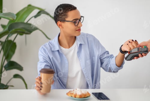 Preview: A cheerful young woman in casual attire enjoys contactless payment technology