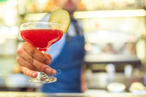Preview: The barman holding a red cocktail with a citrus