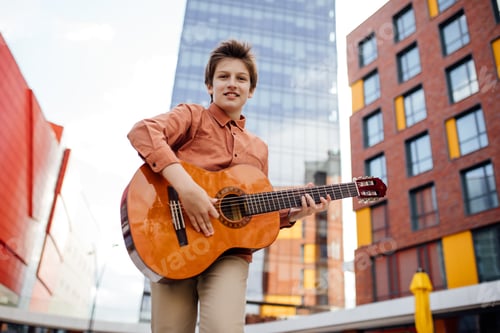 Preview: handsome preteen plays guitar, in the park, look at the camera,