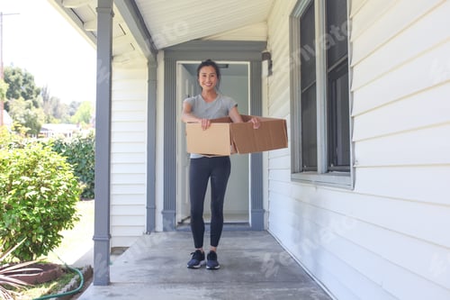 Preview: Woman Carries Box on Porch of Suburban Home
