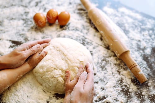 Preview: Close up hands of mother and son kneading a dough on a wooden table. Family cooking at home together