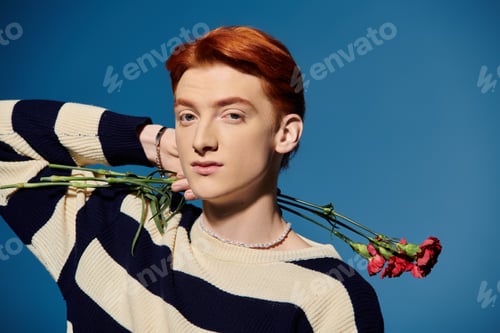 Preview: Emotional young man expressing beauty with flowers in a serene blue backdrop