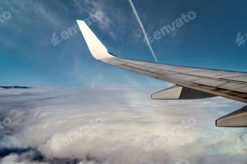Preview: Flying airplane with wing over dense cloud in blue sky