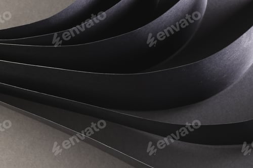 Preview: Close up of rolled up pieces of black paper with copy space on grey background