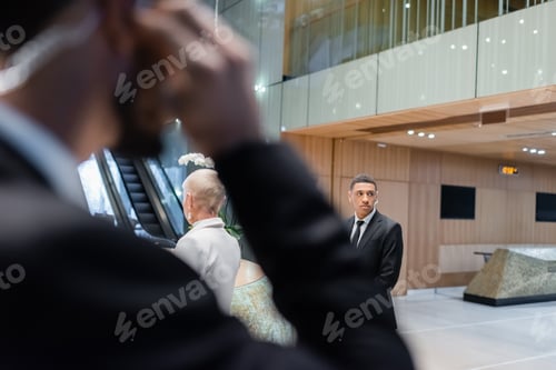 Preview: african american bodyguard protecting senior businesswoman in hotel near bi-racial security man