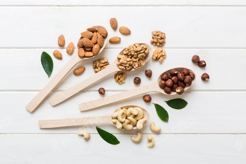 Preview: mixed nuts in white wooden spoon. Mix of various nuts on colored background