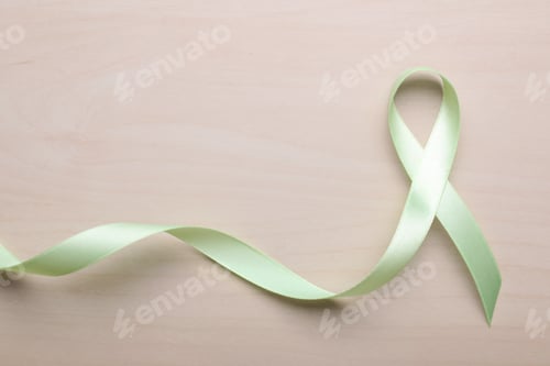 Preview: World Mental Health Day. Green ribbon on wooden background, top view with space for text