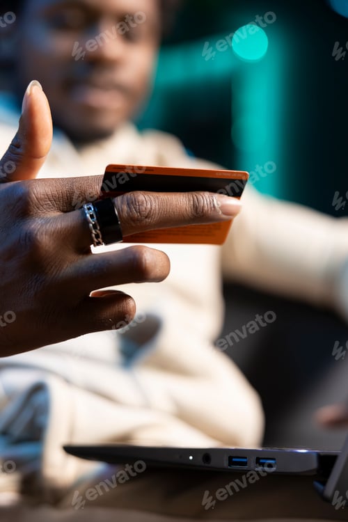 Preview: Focus on credit card held by person in blurry background doing internet shopping