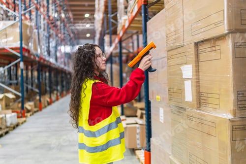 Preview: Warehouse young woman worker scanning packages with barcode scanner in logistics center