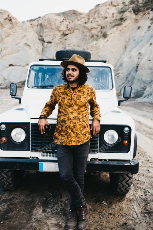 Preview: Stylish man leaning on car hood in canyon