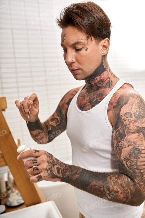 Preview: Handsome tattooed man relaxing at home while engaged in a creative activity