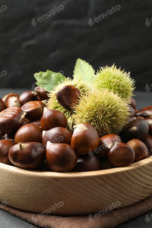 Preview: Fresh sweet edible chestnuts in wooden bowl on table, closeup
