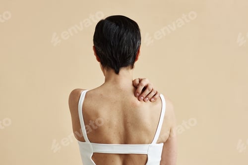 Preview: Woman hiding standing with bare back against minimal beige background