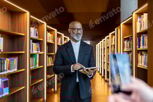 Preview: Portrait of smiling businessman with digital tablet at library