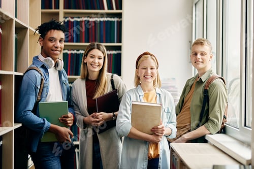 Preview: Portrait of happy university students in a library looking at camera.