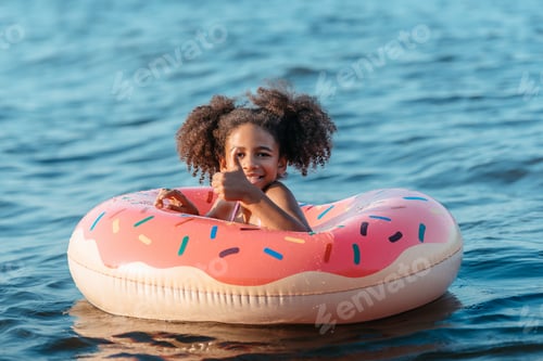 Preview: cute smiling african american girl swimming on airmatress and showing thumb up