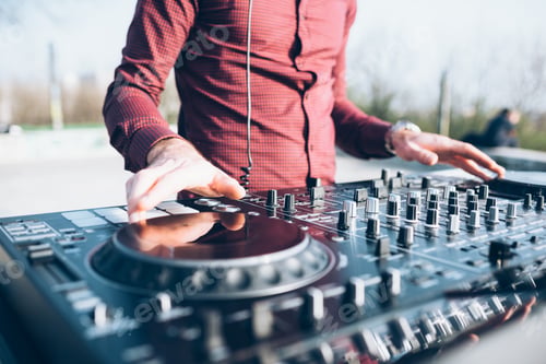 Preview: Young man using mixing desk at roof party, mid section, close-up