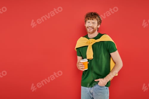 Preview: morning coffee, redhead man with beard and curly hair holding paper cup on coral background,