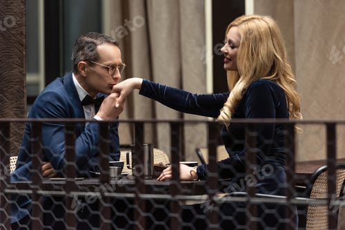 Preview: handsome adult man kissing hand of girlfriend at restaurant
