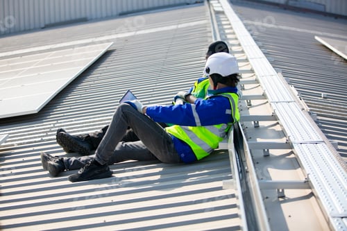 Preview: Professional worker installing solar panels on the roof of a house.