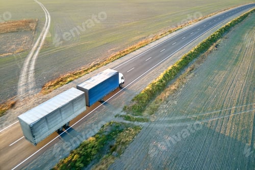 Preview: Aerial view of blurred fast moving semi-truck with cargo trailer driving on highway hauling goods in