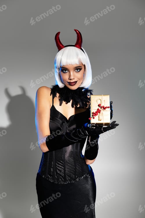 Preview: A young woman embraces Halloween spirit in a striking costume while presenting a mysterious gift