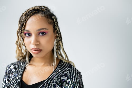 Preview: portrait of african american woman looking at camera on grey background, bold makeup, earrings