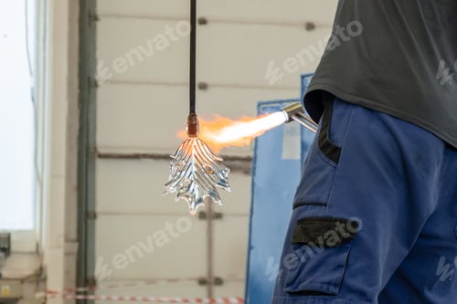 Preview: A man uses a gas burner to melt glass. A craftsman makes a glass in a leaf shaped