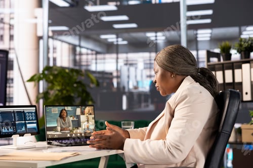 Preview: Businesswoman looking over business revenue charts with employees in videocall