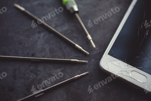 Preview: Smartphone with a broken screen and repair tools.